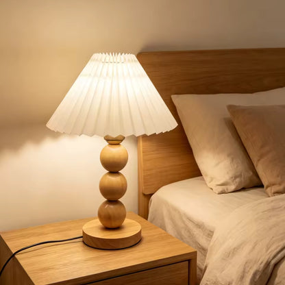 Oren wood table lamp glowing on a natural bedside table