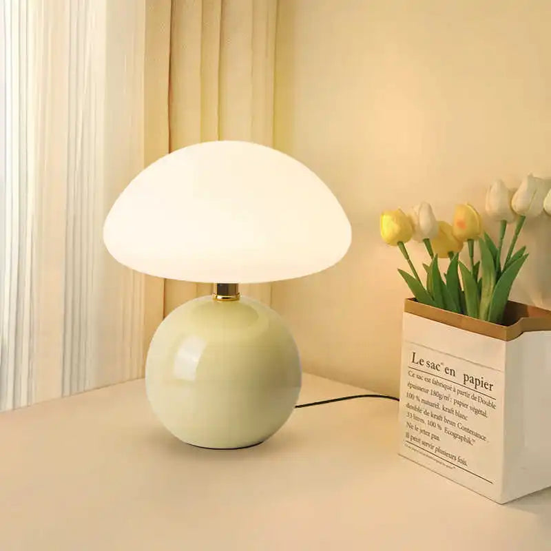 Cream Pola ceramic table lamp glowing beside flowers