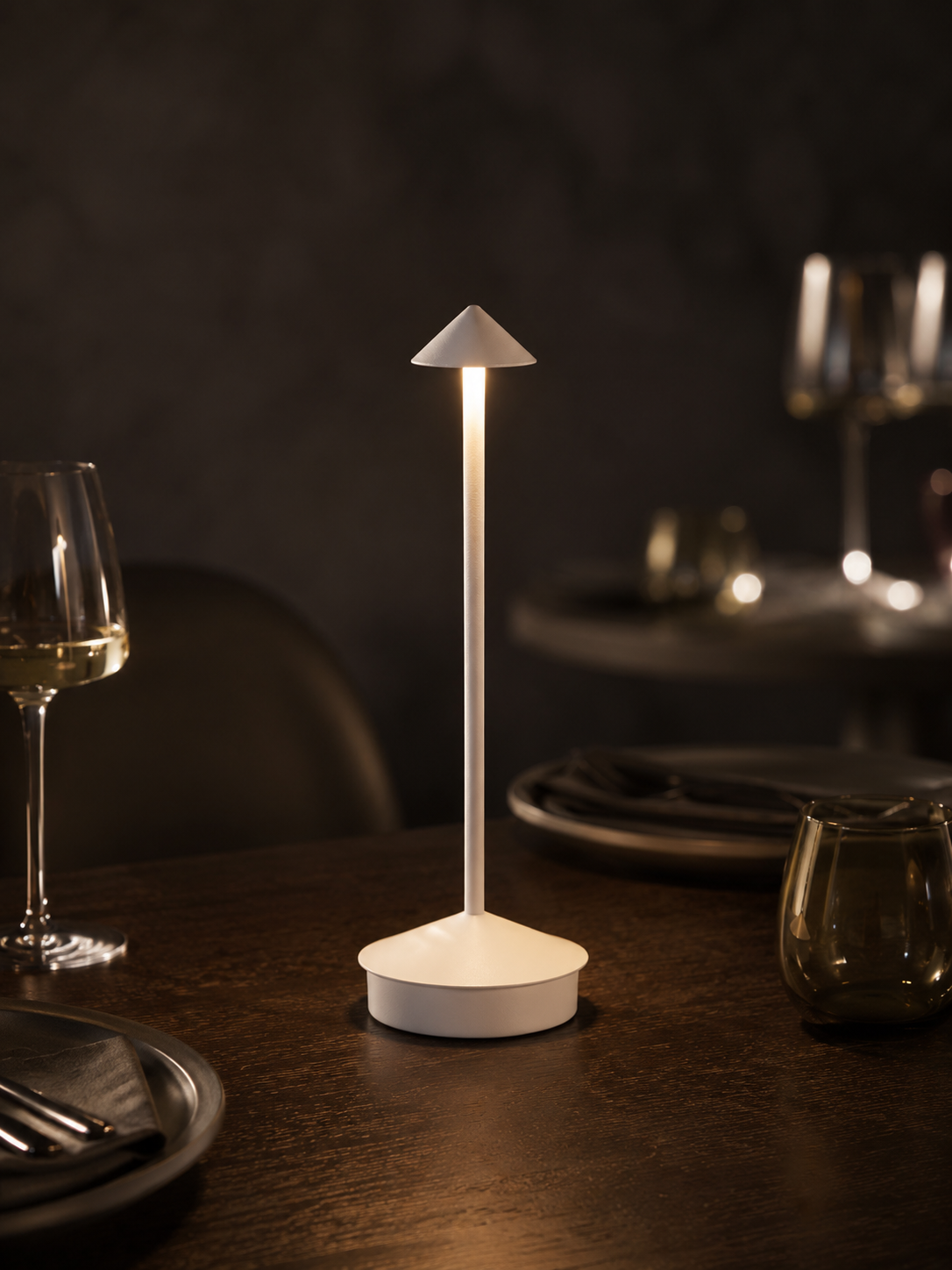 Lumae Aura cordless lamp glowing on a dark oak dining table