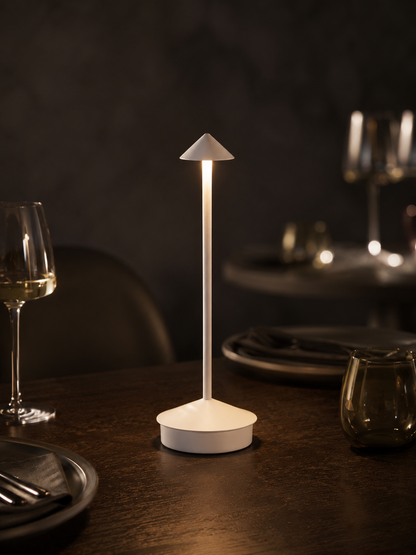 Lumae Aura cordless lamp glowing on a dark oak dining table