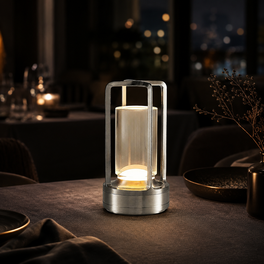 Lumae Marlow cordless lamp in silver lit on a dark restaurant table at night