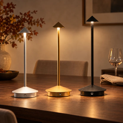Silver, gold, and black Mirelle cordless table lamps glowing on a walnut dining table