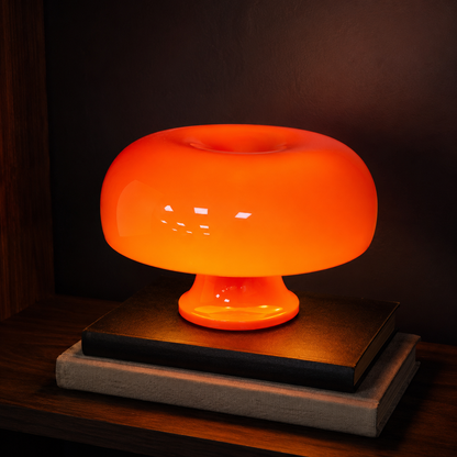 Oslo orange moulded acrylic dome lamp lit on a stack of books, part of The Amber Pair