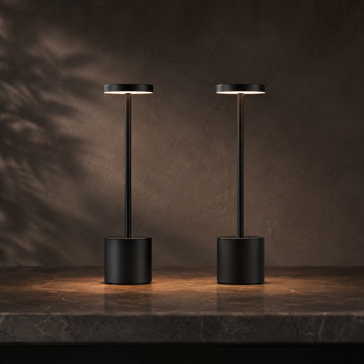 Lumae Vesper cordless table lamps in matte black on stone at dusk