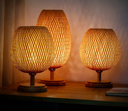 Willow hand-woven bamboo table lamps, Tall and Wide, glowing on a wood console