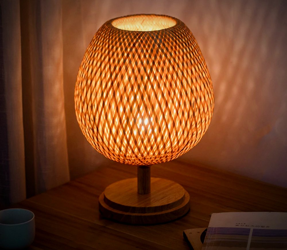 Willow Wide bamboo table lamp lit in a living room corner