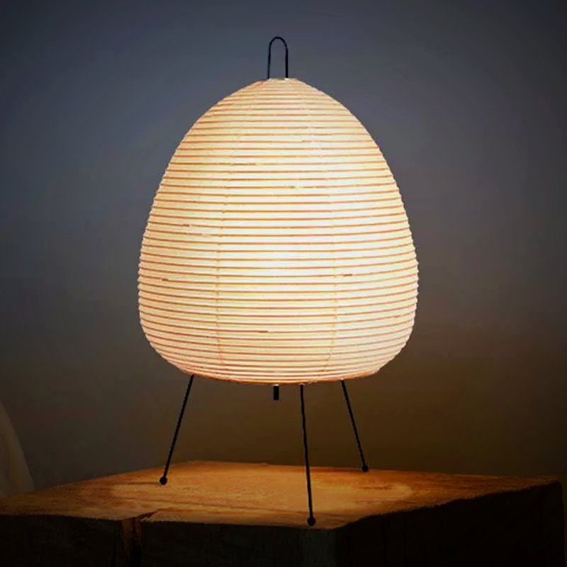 Lumae Yumi paper lantern tripod table lamp lit on a wood block